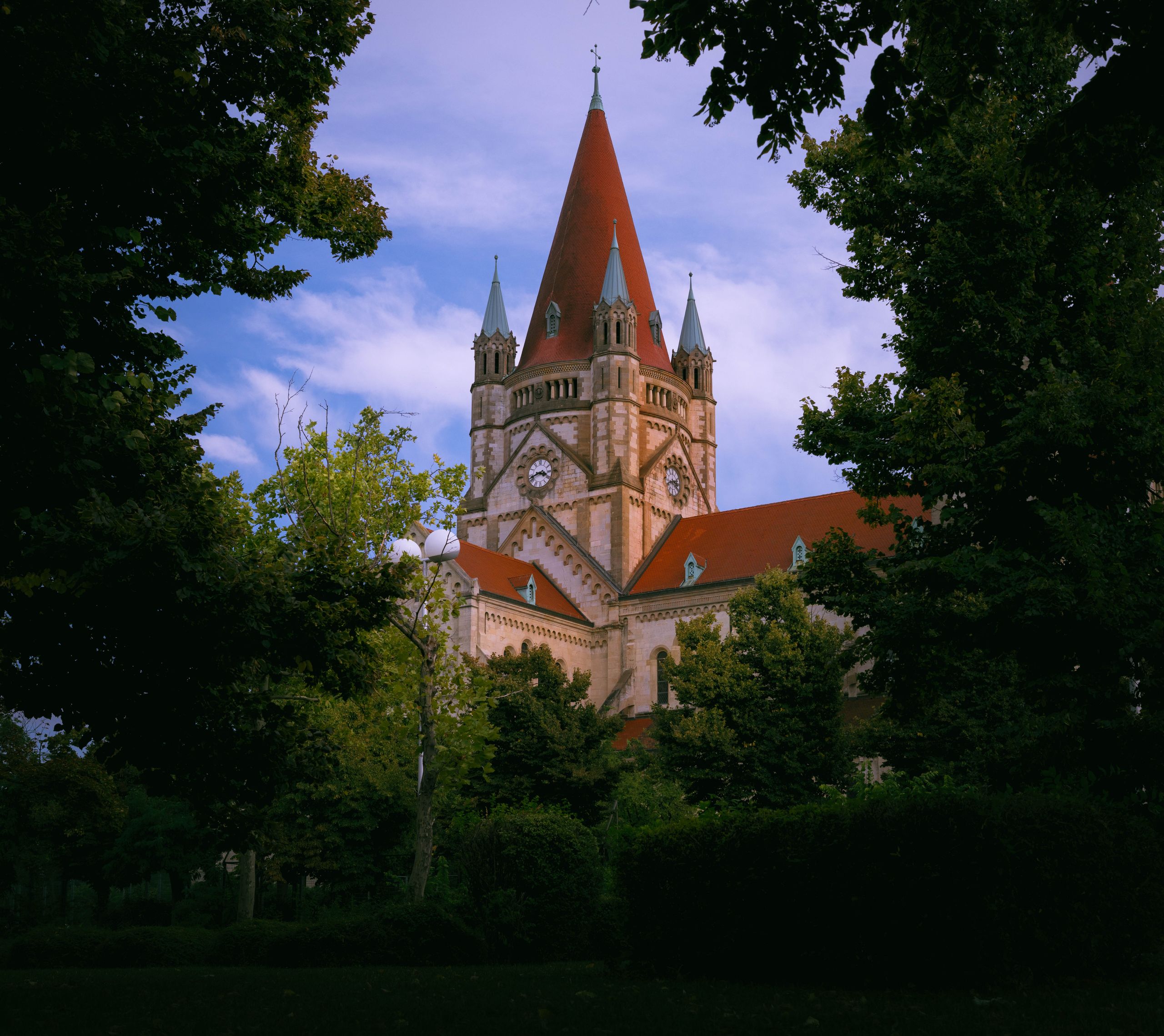 Beautiful capture of St. Francis of Assisi Church in Vienna framed by lush greenery.